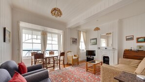 Ein geräumiges Wohnzimmer mit großem Fenster, Kamin und Fernseher.