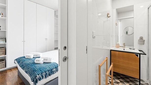 A modern hotel room with a bed, a bathroom with a mirror, and a wardrobe. - GuestReady - Charming Porto Retreat Near the Sea (Porto)