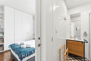 Una habitación de hotel moderna con una cama, un baño con espejo y un armario.