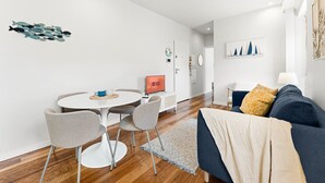 A modern living room with a round dining table, grey chairs, a blue sofa, and a TV displaying "GUEST READY". - GuestReady - Charming Porto Retreat Near the Sea (Porto)