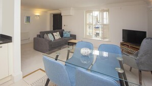 Un apartamento moderno con comedor, sofá, televisor y ventana con persianas.