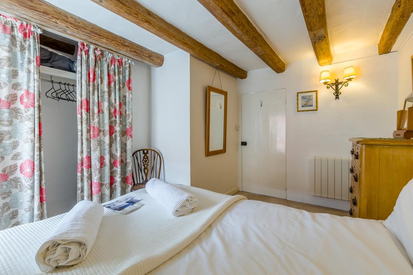 Una camera da letto con un letto, una testiera in legno, una sedia, un armadio, uno specchio e un punto luce a parete.