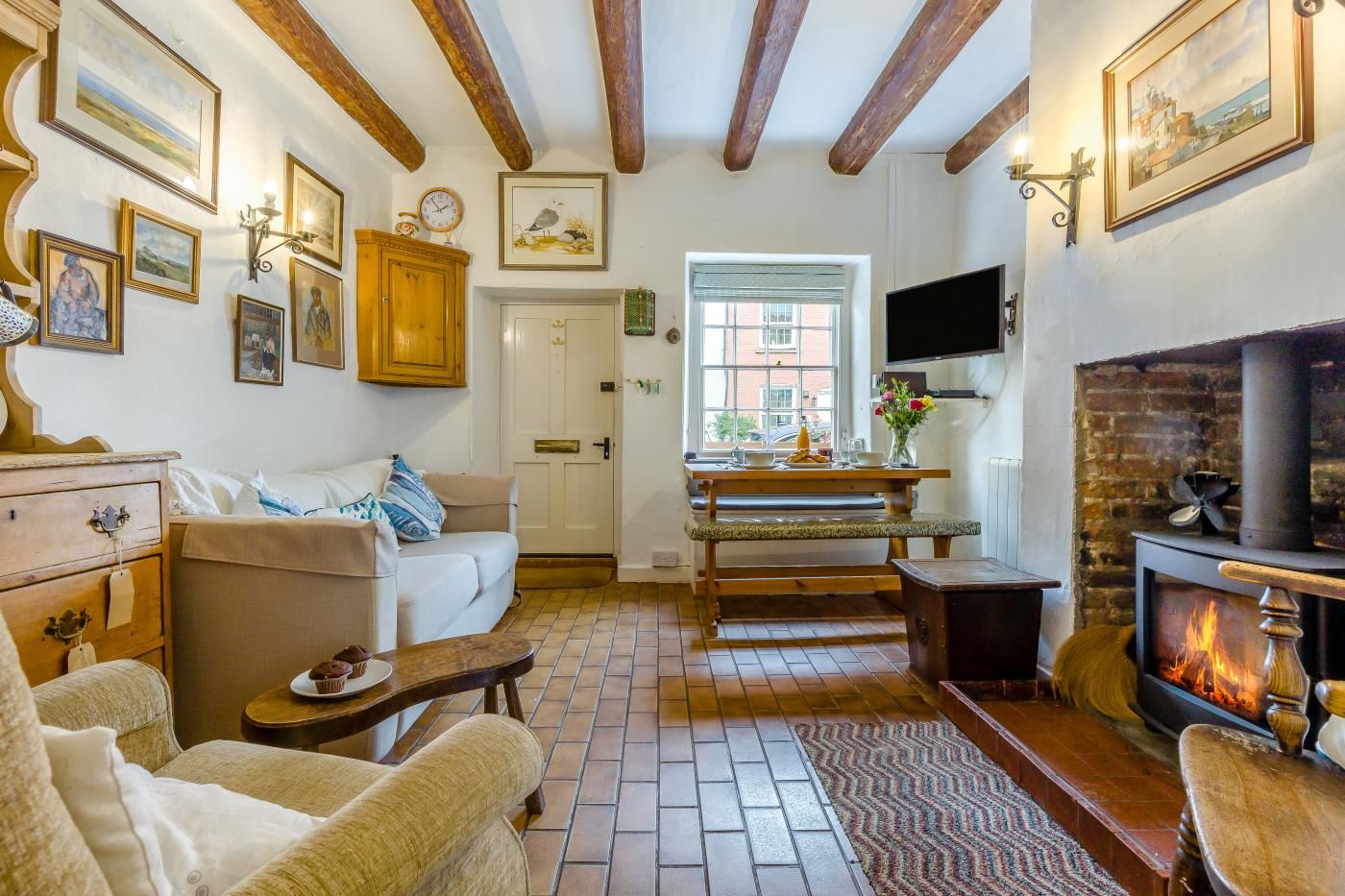 A cozy living room with a fireplace, wooden beams, a dining area, and a television.