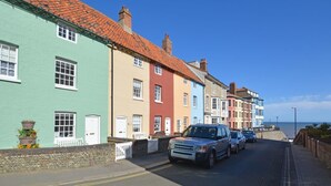 A row of colorful houses along a coastal road with a clear view of the sea.