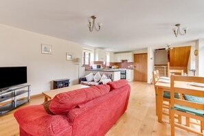 A living room with a red sofa, a TV, and a dining area with a wooden table and chairs. - 2 Bed in Benenden (oc-cb540) (Benenden)