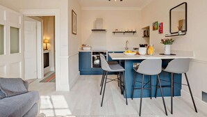 Une cuisine moderne avec des meubles bleus, un plan de travail blanc et un coin repas équipé de trois chaises.