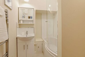 Un baño con lavamanos, espejo y cabina de ducha de vidrio.