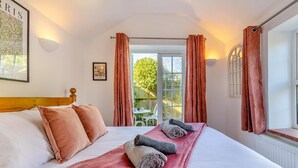 A bedroom with a bed, a window with curtains, a view of the outdoors, and a framed picture on the wall. - 1 Bed in Stiffkey (oc-1642) (Stiffkey)