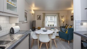 Ett kompakt kök med en matplats, en TV och ett fönster med gardiner.