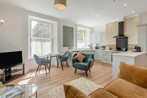 Una sala de estar moderna con televisor, asientos y comedor.