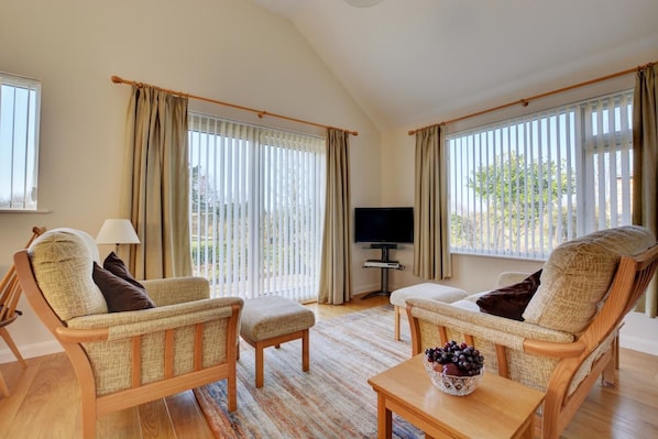 A spacious living room with two armchairs, a coffee table, and a TV stand. - 2 Bed in Attleborough (oc-1277) (Old Buckenham)