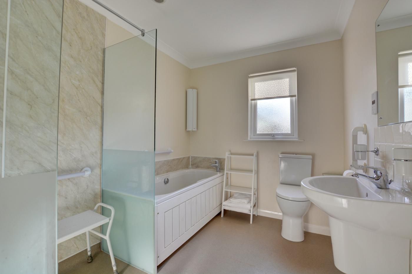 A modern bathroom with a glass shower enclosure, a bathtub, a toilet, and a sink.
