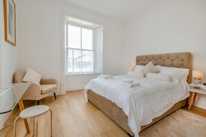 Une chambre avec un grand lit, une chaise, un bureau et une fenêtre.