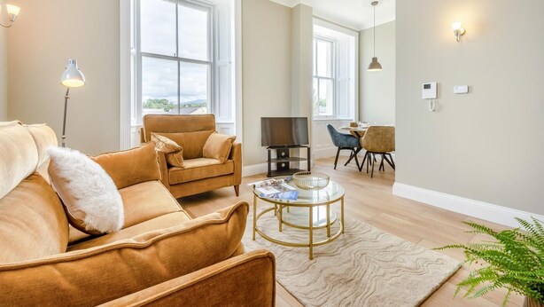 Una sala de estar con sofá, sillón y mesa de centro, televisor y un comedor con sillas y mesa.