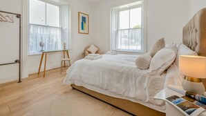 Un dormitorio con una cama, un escritorio y dos ventanas.