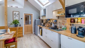 Een moderne keuken met dakramen, witte kasten en een houten eettafel.