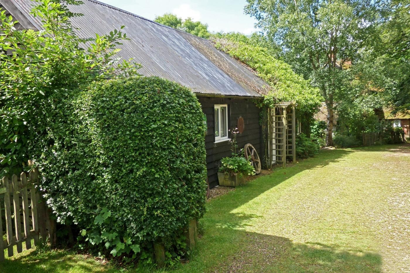 Une maison rustique en bois, surmontée d’un toit en métal, entourée d’une végétation luxuriante et d’une pelouse bien entretenue.