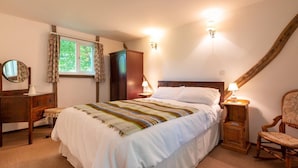 Un dormitorio con una cama grande, un aparador de madera, una silla y una ventana con cortinas.