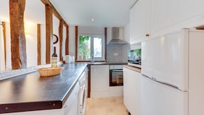 Una cocina moderna con armarios blancos, encimera de acero inoxidable y horno empotrado.