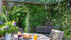 Una mesa de madera con un plato, un frasco de mermelada, un vaso de jugo de naranja y un croissant.