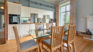A modern kitchen with white cabinets, a glass dining table, and wooden chairs. - 2 Bed in Binham (oc-1477) (Binham)