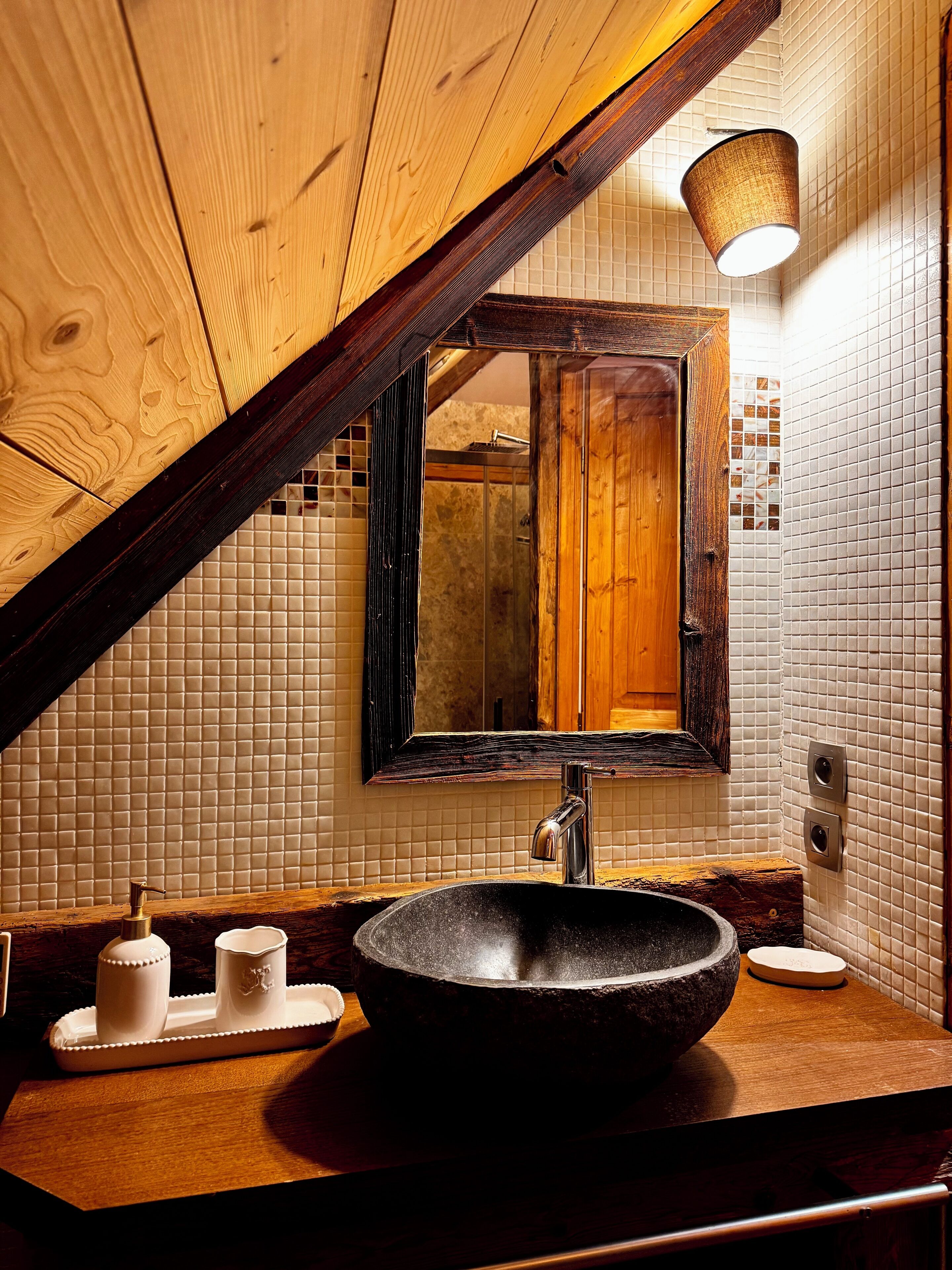 Een badkamer met een houten wastafelmeubel, een ruime wastafel, een spiegel en een handdoekrek.