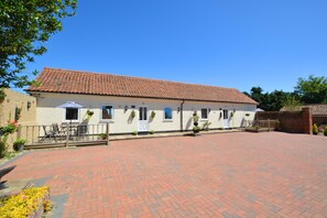 A two-story building with a tiled roof, a paved courtyard, and outdoor seating. - 1 Bed in Blofield Heath (oc-1468) (Blofield)