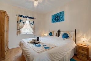 A bedroom with a bed, bedside tables, a window with curtains, a painting on the wall, and a chandelier. - 1 Bed in Blofield Heath (oc-1468) (Blofield)