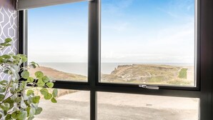 A room with a large window offering a view of a coastal landscape. - 3 Bed in Tintagel (oc-e32938) (Tintagel)