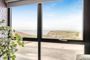 A room with a large window offering a view of a coastal landscape. - 3 Bed in Tintagel (oc-e32938) (Tintagel)
