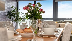 A dining table set with plates, glasses, and a vase of flowers. - 3 Bed in Tintagel (oc-e32938) (Tintagel)
