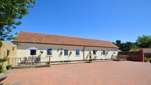 A two-story building with a tiled roof, a paved courtyard, and outdoor seating. - 2 Bed in Blofield Heath (oc-1467) (Hemblington)