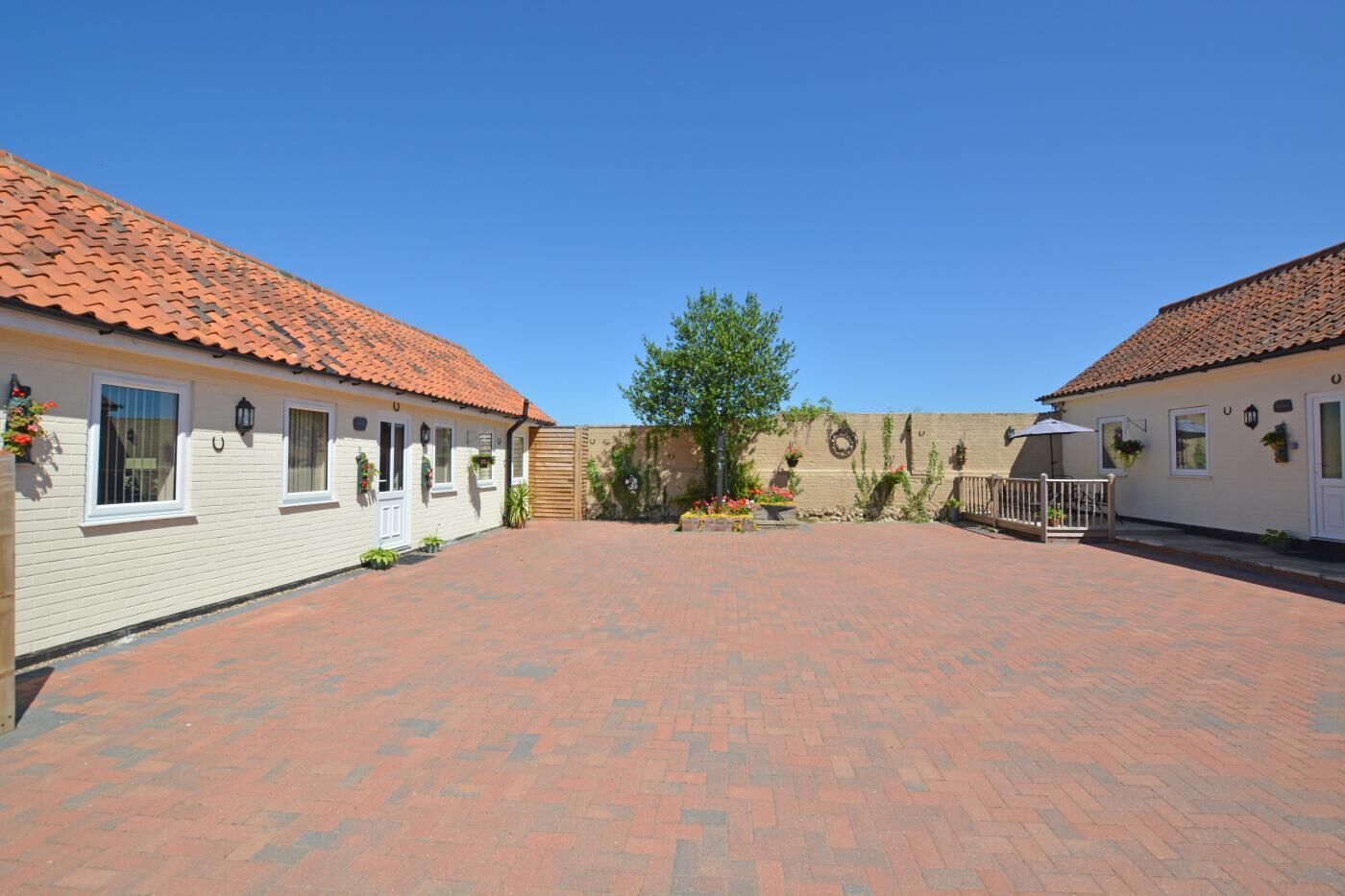 A courtyard with two white buildings, each with a red-tiled roof and white-framed windows.