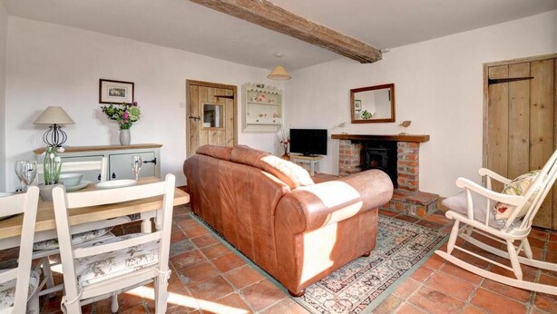 A living room with a sofa, a television, a fireplace, and a dining area with a table and chairs. - 2 Bed in Bodham (oc-1660) (Bodham)