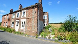 A two-story brick house with multiple windows and a chimney, surrounded by a rural landscape. - 2 Bed in Bodham (oc-1660) (Bodham)