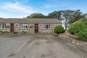 A stone building with a front door, windows, and a gravel driveway. - 1 Bed in Llandeloy (oc-c32808) (Llandeloy)