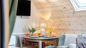 A cozy dining area with a wooden ceiling, a table set with plates, a lamp, and flowers. - 1 Bed in Horton (oc-b32802) (Horton)