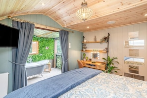 A bedroom with a bed, a vanity with a mirror, and a bathtub. - 1 Bed in Horton (oc-b32802) (Horton)
