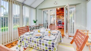 A conservatory with a dining table set for breakfast, large windows, and a view of the garden. - 2 Bed in Briston (oc-1551) (Briston)