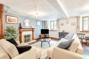 A living room with a fireplace, a television, and a sofa. - 3 Bed in Sedbergh (oc-d32862) (Millthrop)