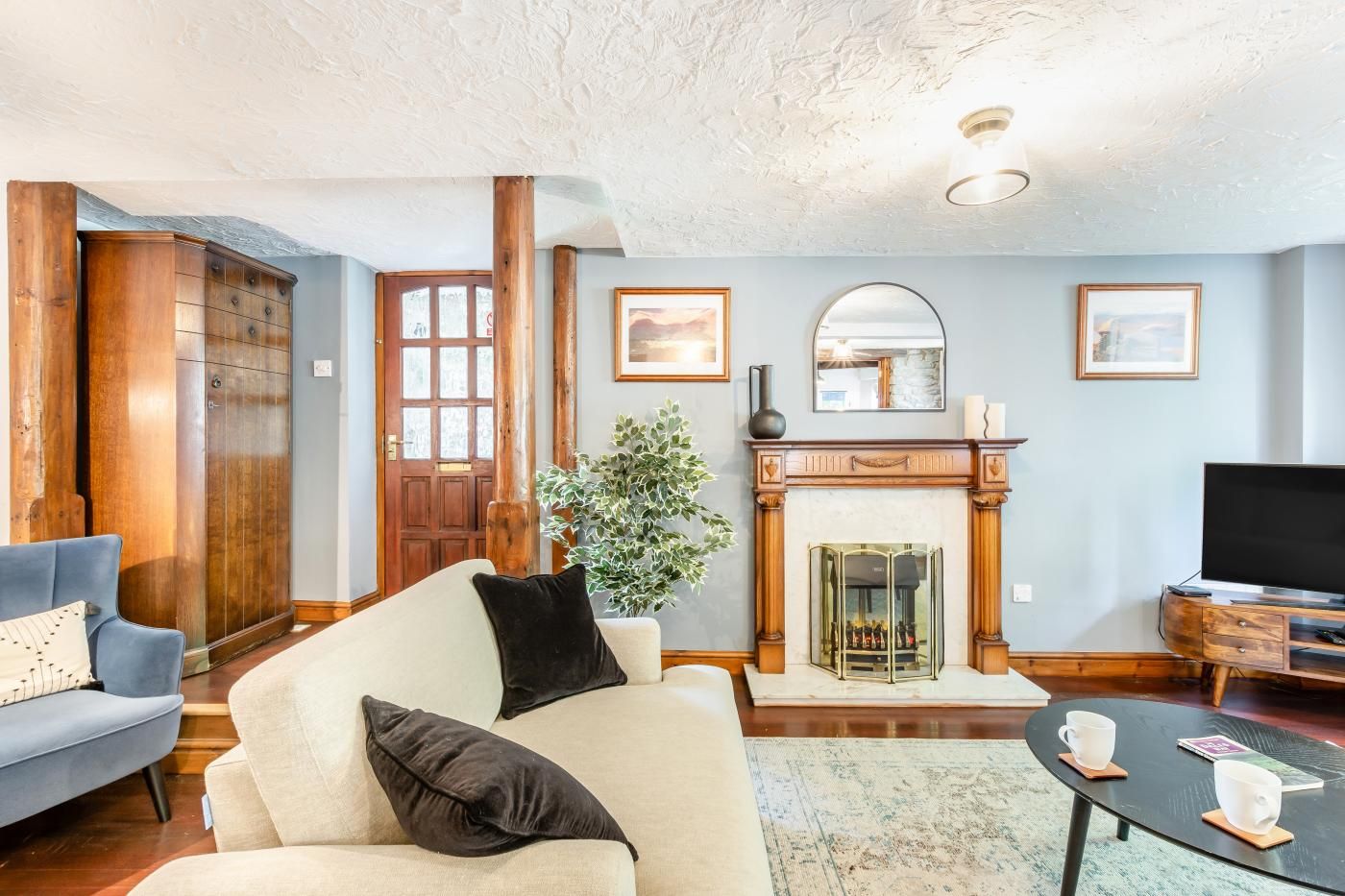 Una sala de estar con sofá, mesa de centro, chimenea y televisor.