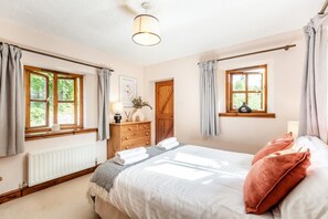 Une chambre à coucher avec un lit, une commode, une fenêtre et une porte.