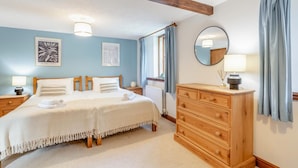Een slaapkamer met een tweepersoonsbed, een houten hoofdbord, nachtkastjes met lampen, een dressoir en kunstwerken aan de wanden.