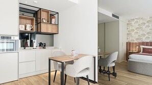 A modern kitchen with built-in appliances, a dining area with two chairs, and a cozy seating area with a sofa and a bed. - GuestReady - Alma Invicta 'Ribeira I' (Porto)
