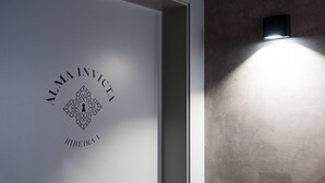A wall with a sign reading "ALMA INVICTA RIBICIRA 1" and a wall-mounted light fixture. - GuestReady - Alma Invicta 'Ribeira I' (Porto)