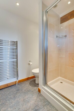 Ein Badezimmer mit einer Duschkabine, Toilette und Handtuchhalter.