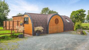 A wooden barn with a sloped roof, a wooden door, and a small window.