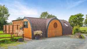 A wooden barn with a sloped roof, a wooden door, and a small window.