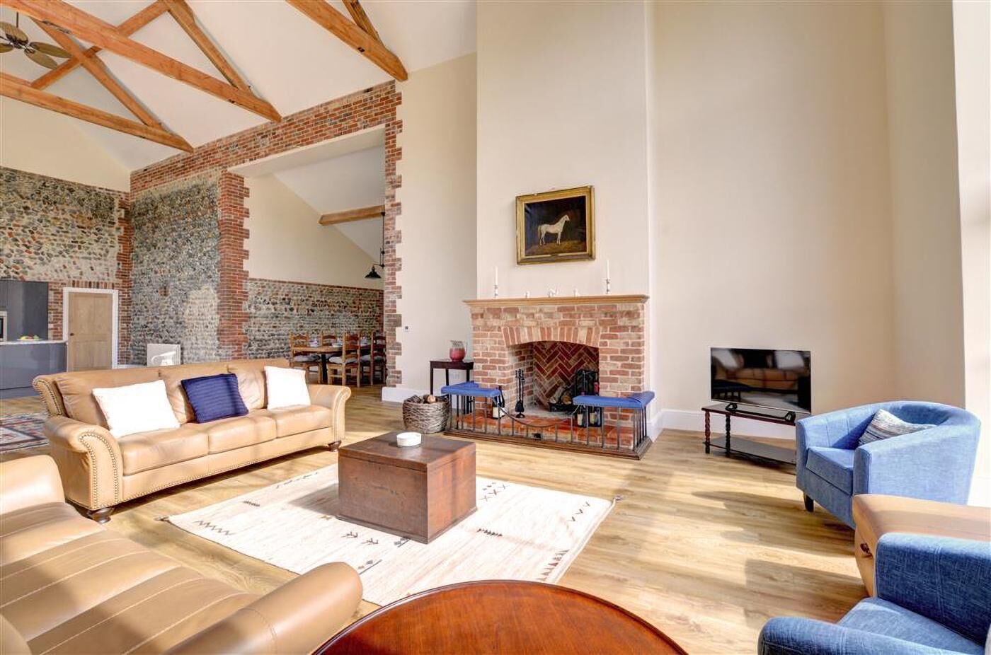 A spacious living room with a brick fireplace, a sofa, a coffee table, and a television.