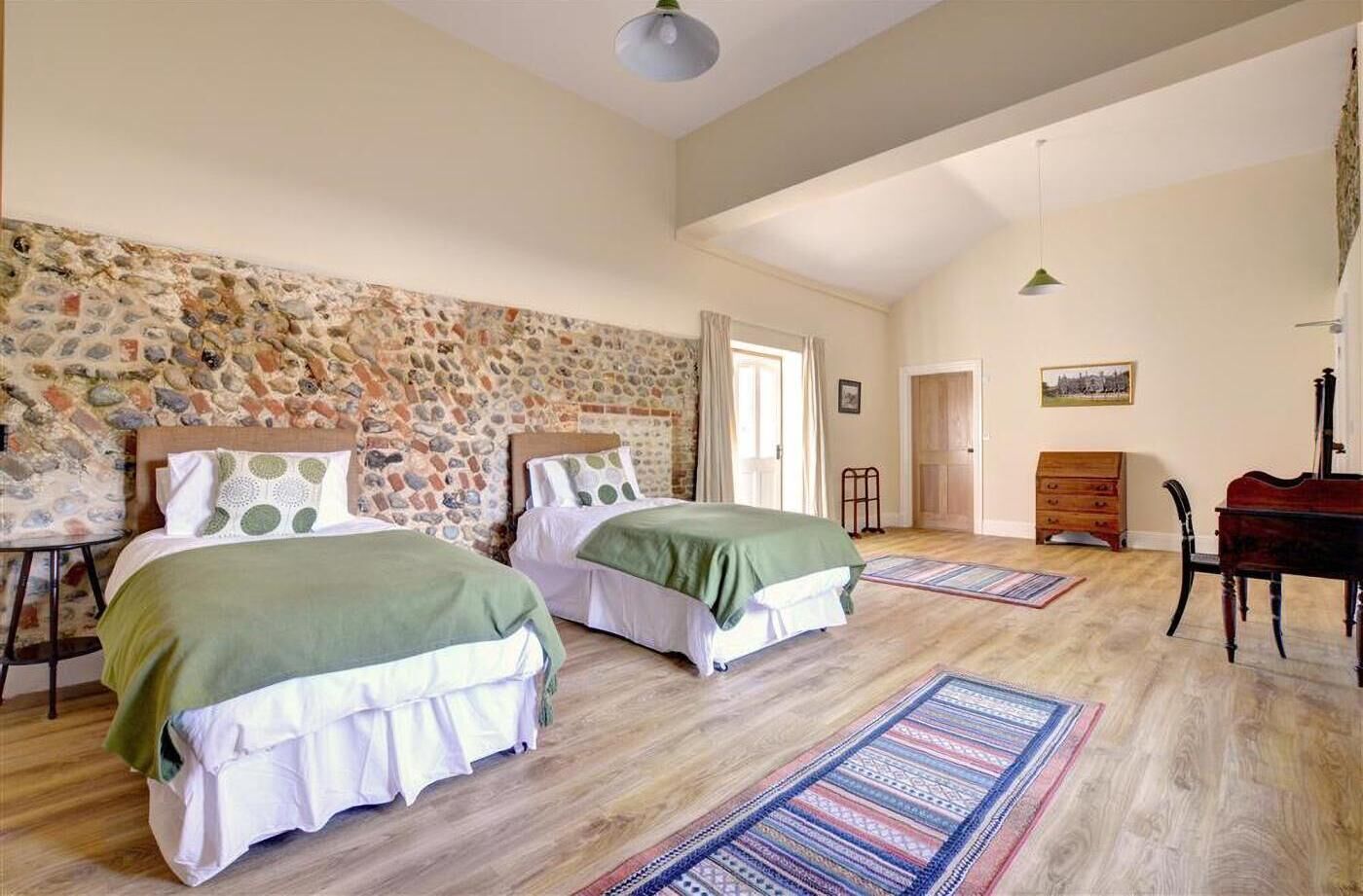 Quarto com duas camas, um piano e uma parede de pedra.